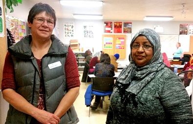 With a refugee language class in the background, YWCA CEO Donna Brooks stands with Amna Hamid, a settlement services worker. Photo by Chelsea Laskowski